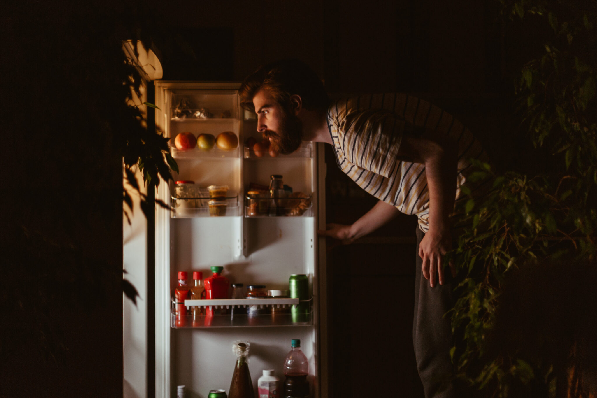 Man looking for snacks in the refrigerator late night